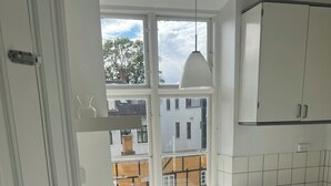 Eine Küche mit Einbauwaschmaschine, Spüle und Fenster mit Blick auf Gebäude.