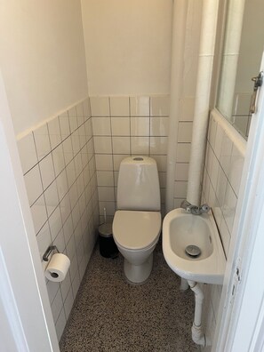 Une petite salle de bain carrelée, équipée de toilettes, d’un bidet et d’un lavabo.
