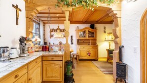 Une cuisine rustique avec des armoires en bois, un poêle et un plafond en bois.