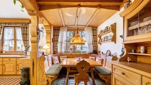 Une salle à manger traditionnelle en bois, avec une grande table, des bancs et un lustre.