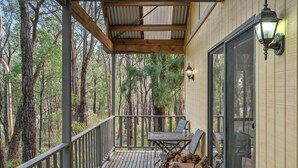 Une terrasse en bois avec une table et des chaises, un foyer et une vue sur la forêt.