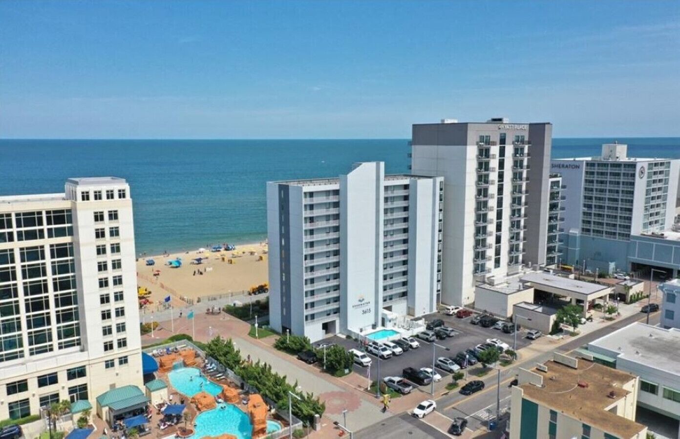Um hotel alto com vários andares, área de piscina e vista para a praia.