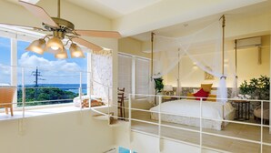 Ein Schlafzimmer mit einem großen Bett, einem Deckenventilator und Blick auf den Ozean.