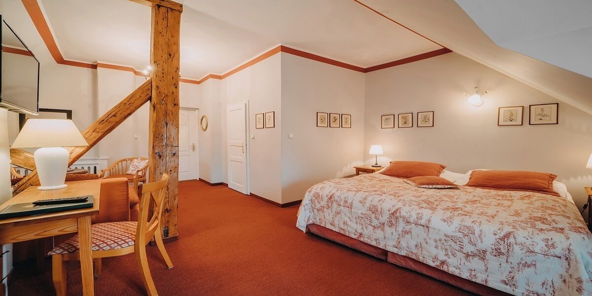 Un dormitorio con cama, escritorio con silla, escalera de madera y una puerta.