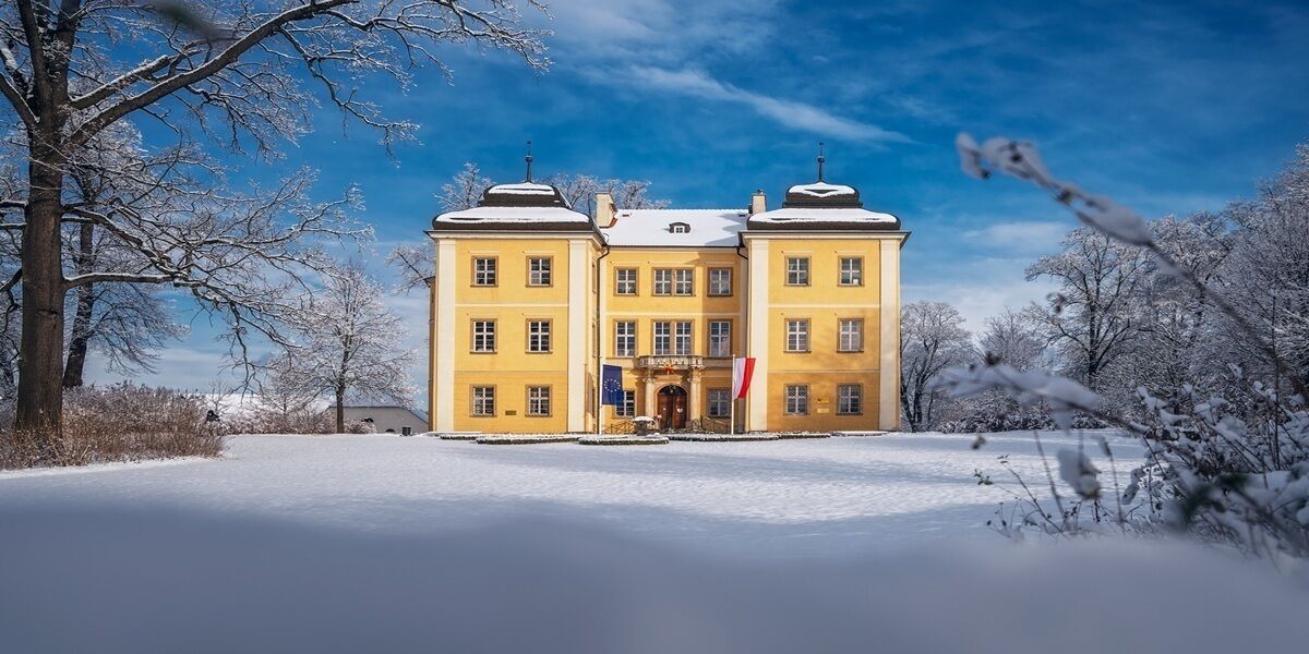 Ein großes, gelbes Gebäude mit einer symmetrischen Fassade, zahlreichen Fenstern und einem zentralen Eingang.
