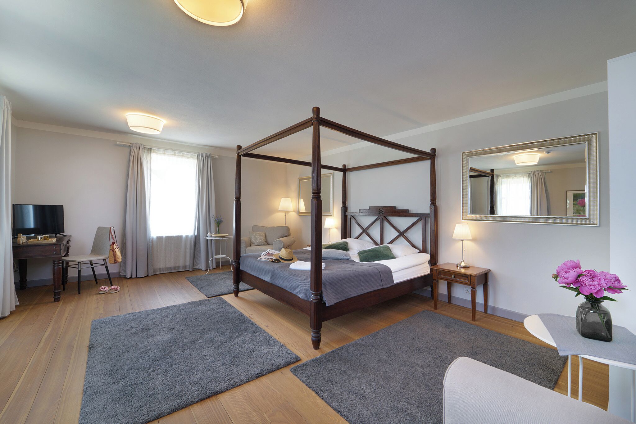 Ein Hotelzimmer mit einem Himmelbett, einem Fernseher, einem Schreibtisch und einem Stuhl.