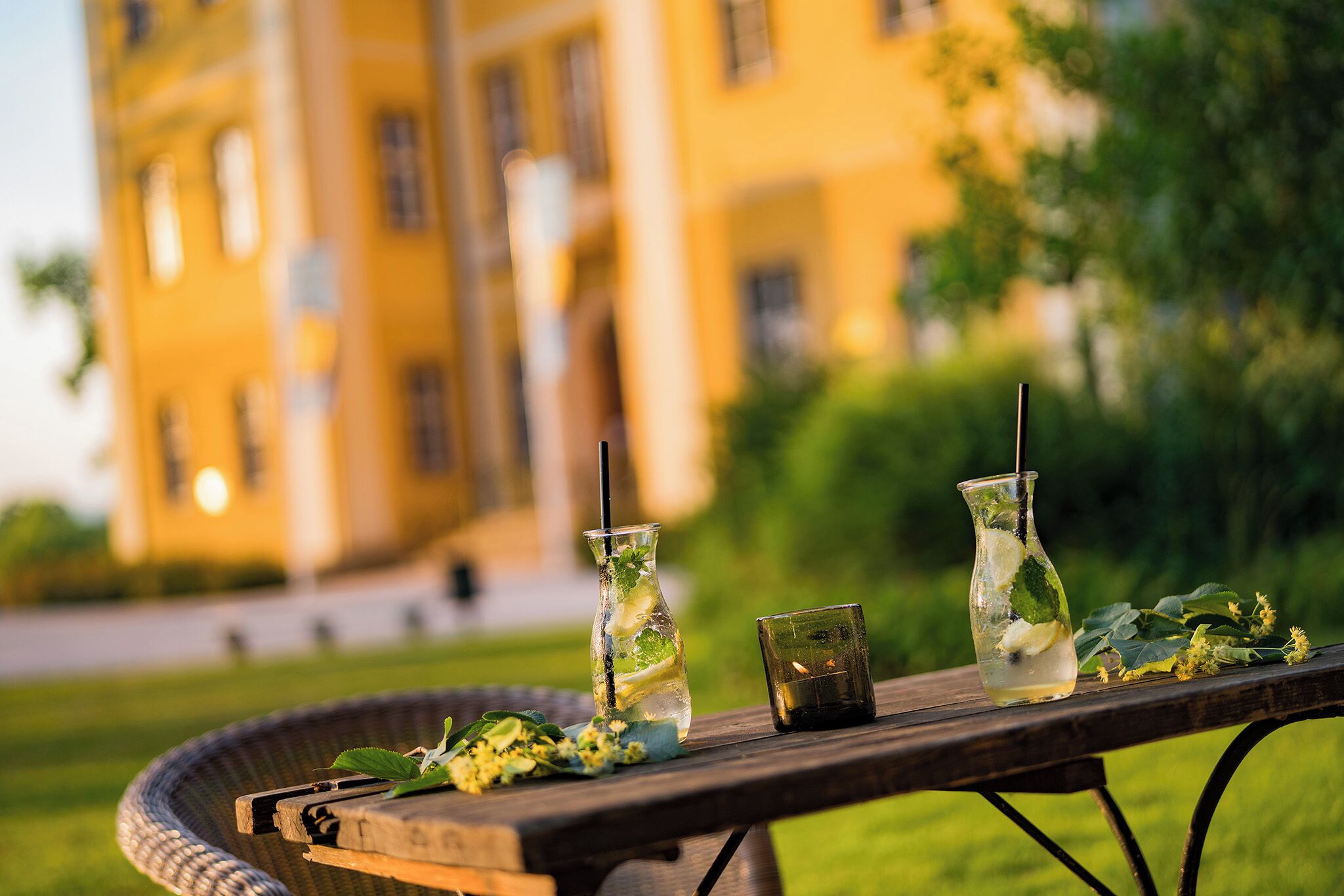 A table with a glass pitcher and a glass, set outdoors with a building in the background.