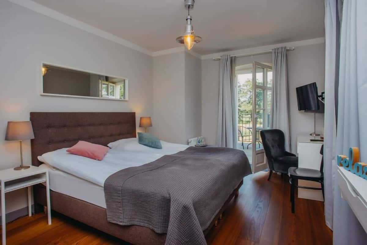 Un dormitorio con una cama grande, lámparas de noche, un televisor de pantalla plana y una silla.