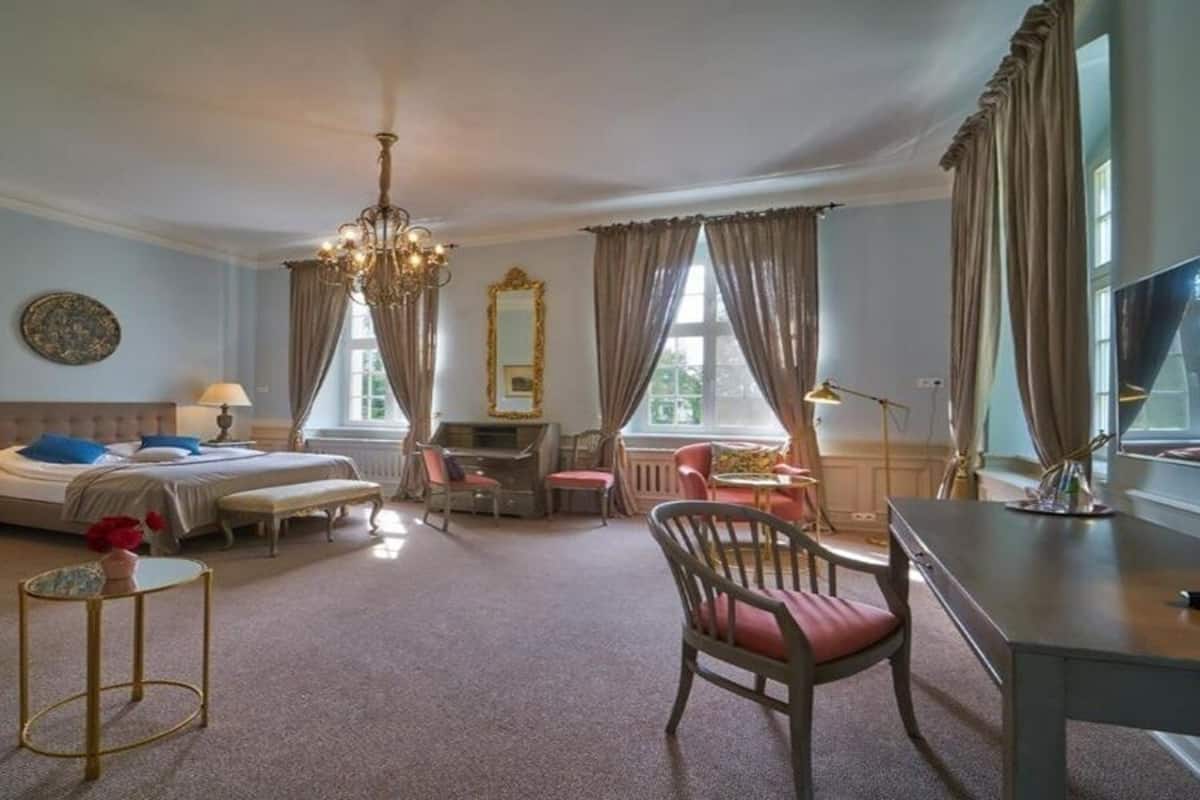 Una habitación de hotel con dos camas, un escritorio, una silla, una mesita y un candelabro.