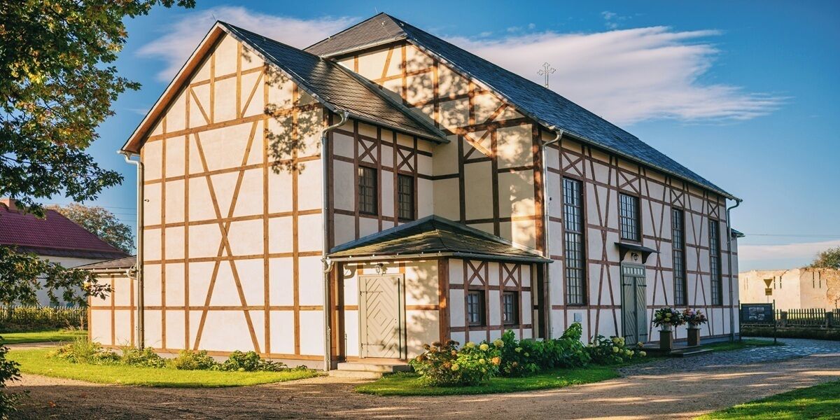 Un edificio tradicional de entramado con fachada simétrica, una entrada central y un pequeño porche.