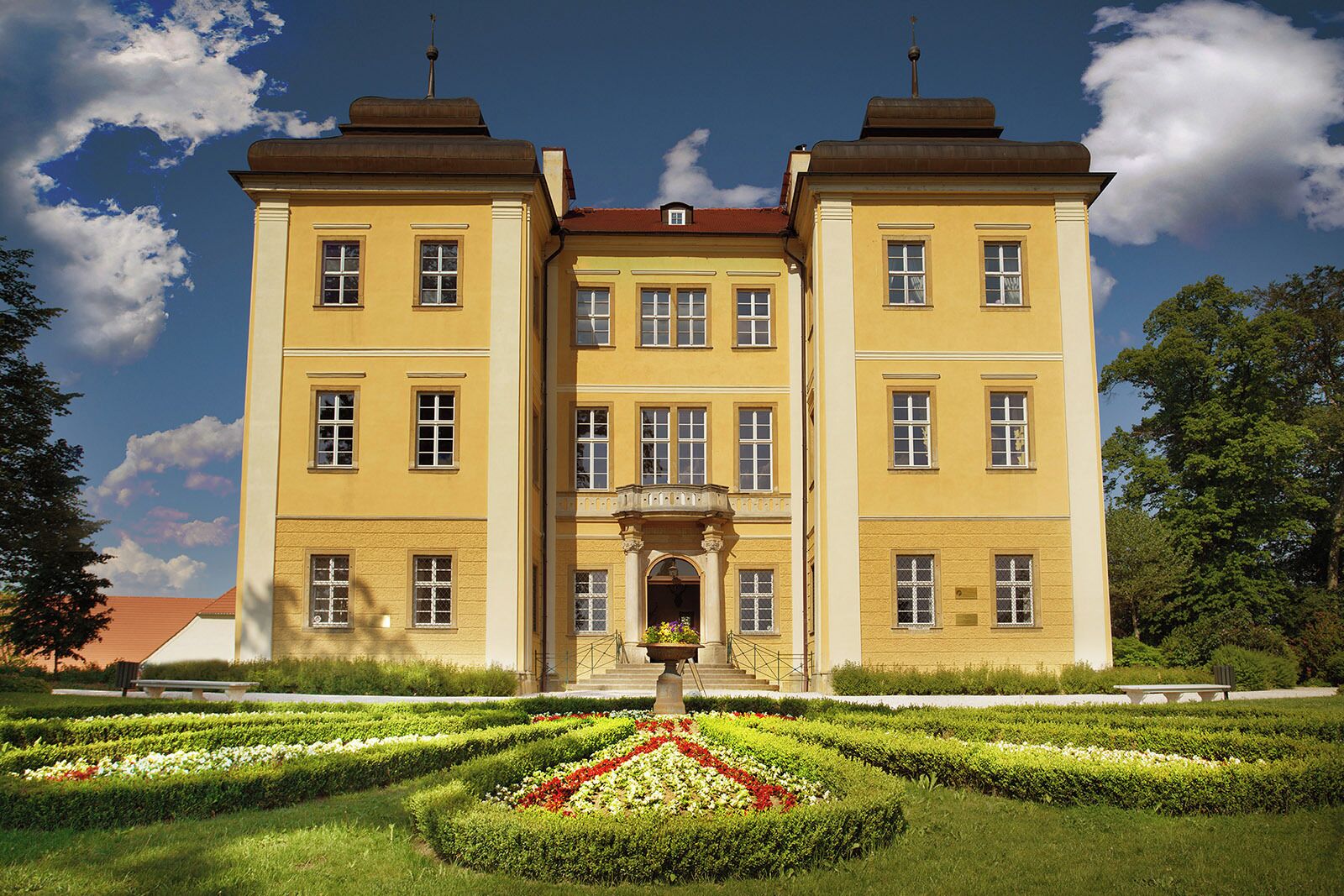 A large, symmetrical building with a central entrance and a formal garden in front.