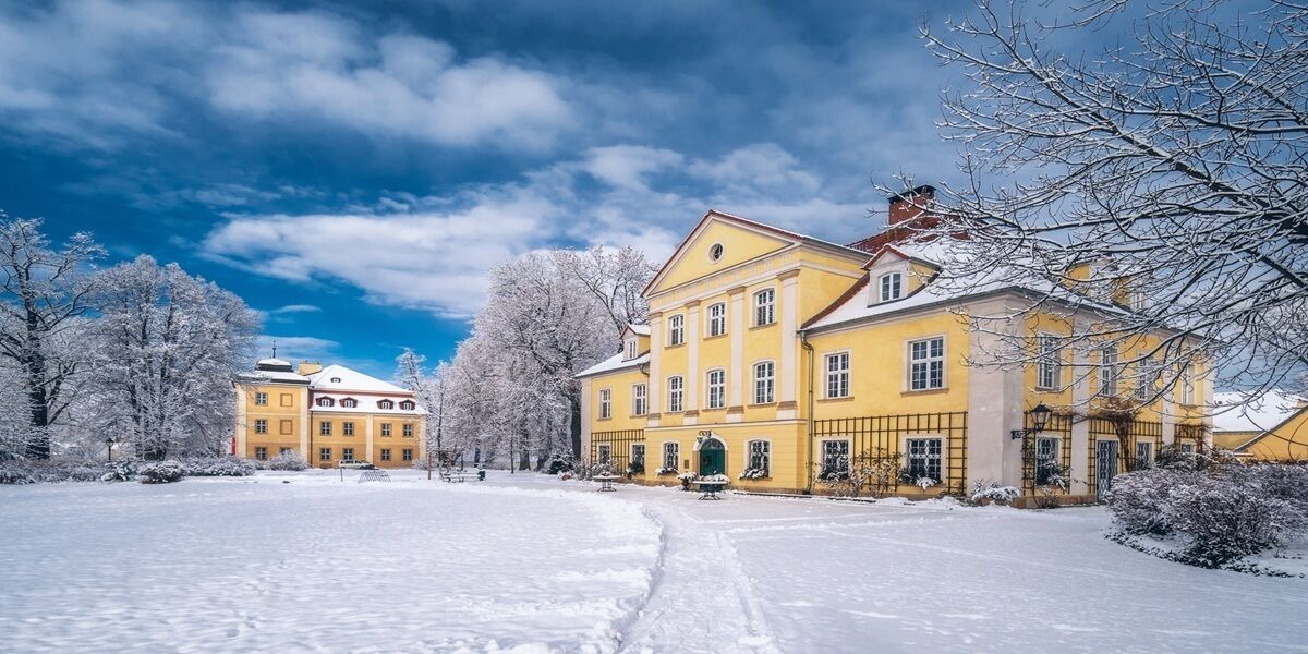 Ein großes, gelbes Gebäude mit einer symmetrischen Fassade, zahlreichen Fenstern und einem zentralen Eingang.