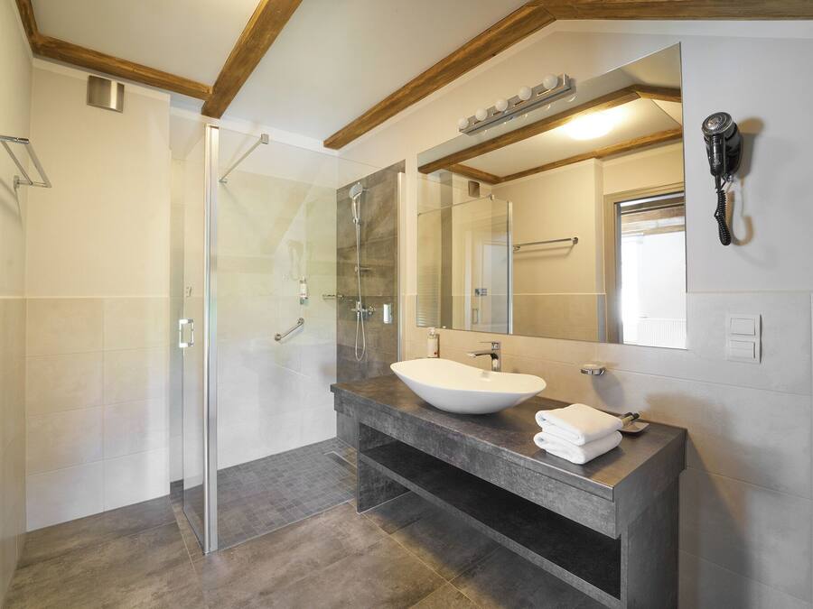 Un baño moderno con cabina de ducha de vidrio, un espejo grande y un lavamanos empotrado.