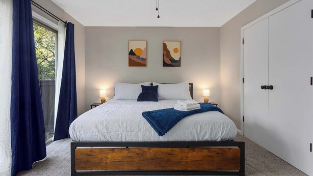 Une chambre à coucher avec un lit, deux lampes fixées au mur, un ventilateur de plafond et une porte.