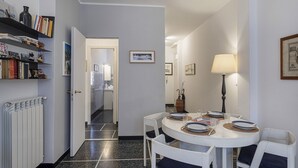 Een eethoek met een ronde tafel voor vier personen, witte stoelen en een witte radiator links.