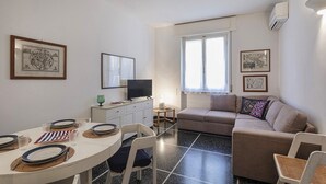 Een ruimtelijke woonkamer met een eethoek, een bank en een televisie.