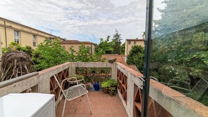 A balcony with a white washing machine, a metal chair, and potted plants.