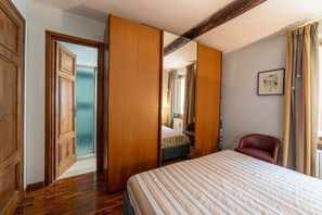 A bedroom with a bed, a chair, a wardrobe, and a mirror.