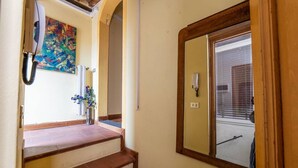 A staircase leading to a room with a large mirror, a telephone, and a wall-mounted air conditioning unit.