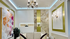A modern living room with a beige sofa, a coffee table, and a chandelier. - Merveil Luxury Suite - Marais - Charlot (Paris)