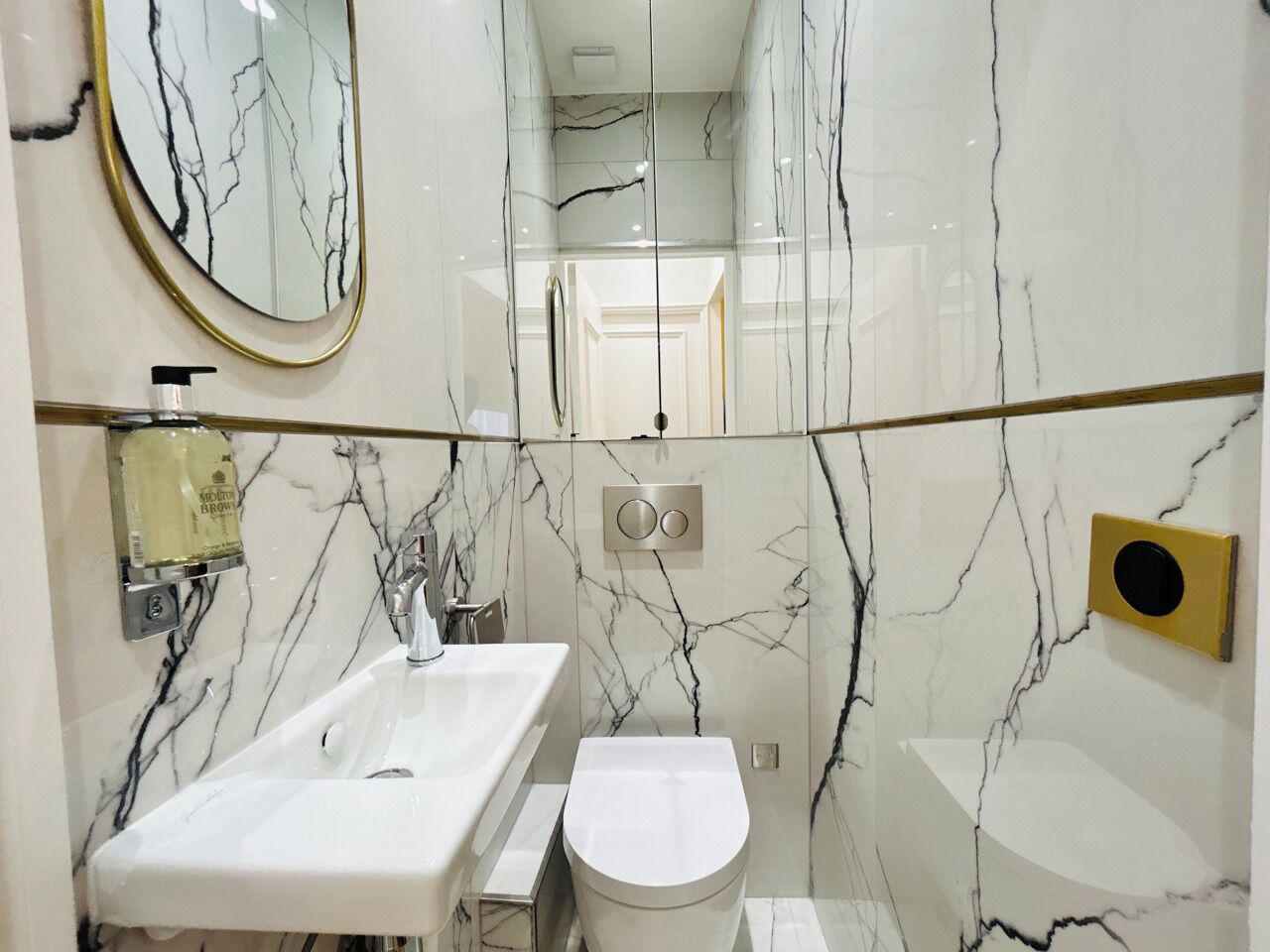 Une salle de bain avec un meuble-lavabo en marbre, des toilettes et un miroir.