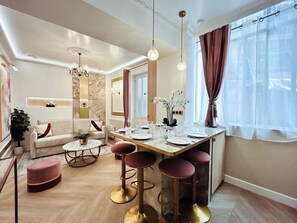 Ein modernes Wohnzimmer mit Essbereich, ausgestattet mit einer Couch, einem Couchtisch und Barhocker.