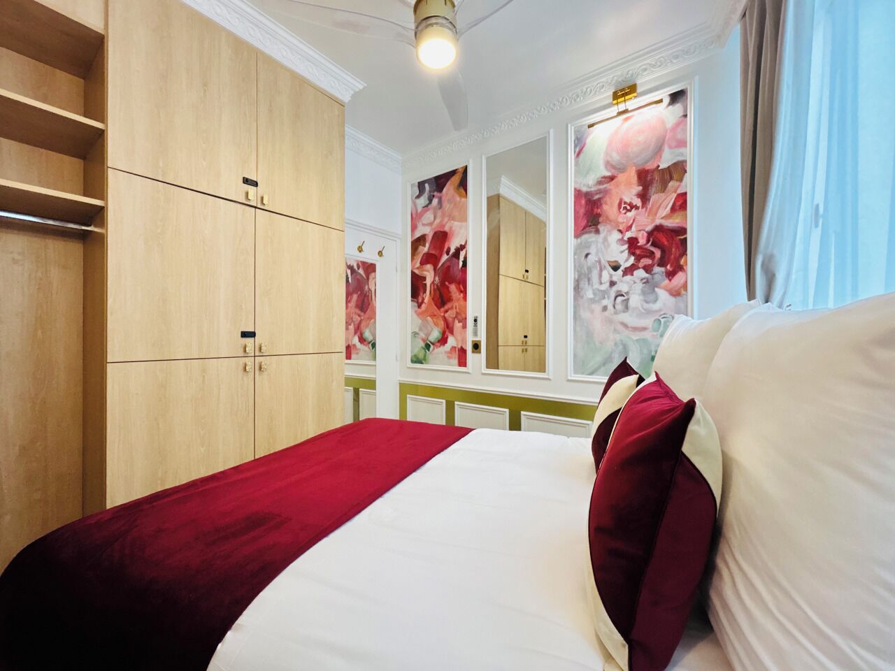 Et hotelværelse med en stor seng, et træskab og et spejl med blomstermotiver.