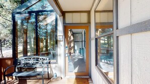 A covered porch with a bench, a glass door leading inside, and a view of the outdoors. - Pet Friendly | Monte Verde Lake | Fireplace | Deer Casa (Angel Fire)