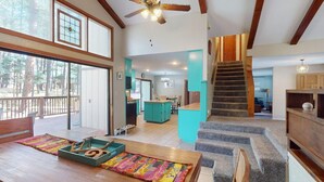 A spacious living area with a wooden staircase, a kitchen, and a dining area. - Pet Friendly | Monte Verde Lake | Fireplace | Deer Casa (Angel Fire)
