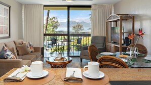 Una camera d'albergo con balcone, zona pranzo e salotto con divano e poltrone.