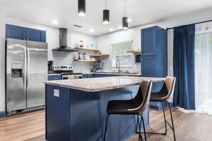 A modern kitchen with a central island, stainless steel appliances, and blue cabinetry. - Spacious Mid-Century Modern Retreat near Spring (Crystal River)