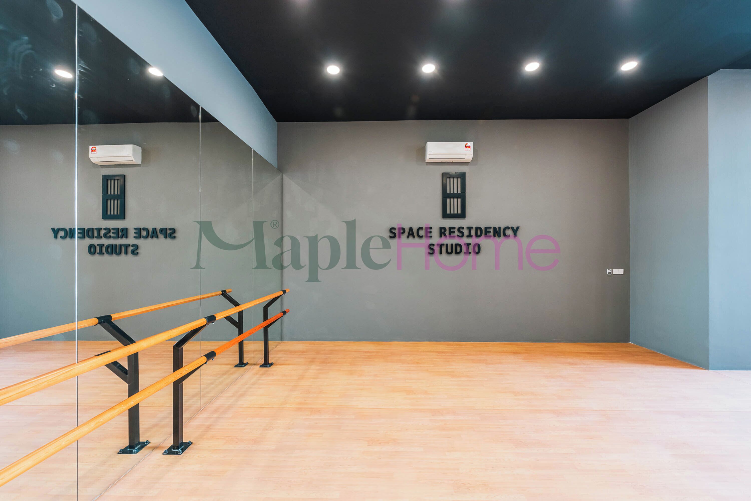 A spacious room with a wooden floor, mirrored walls, and a ballet barre.