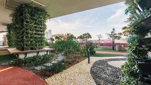 Un espace extérieur moderne agrémenté d’un jardin vertical, d’un chemin de galets et d’un tapis rouge.