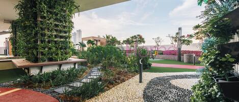 Un espacio exterior moderno con jardín vertical, camino de guijarros y alfombra roja.