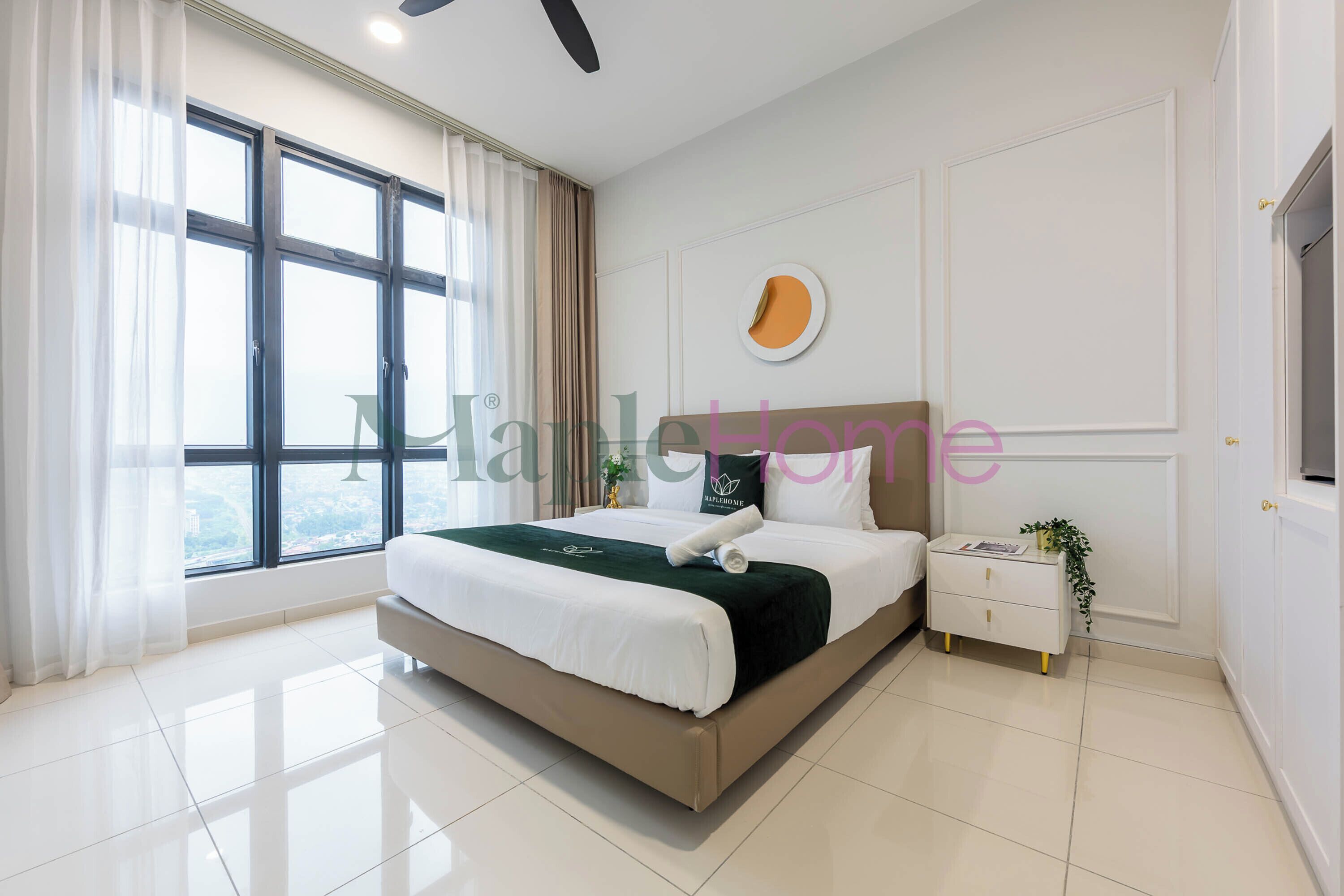 A modern bedroom with a large bed, a bedside table with a plant, and a view through large windows.
