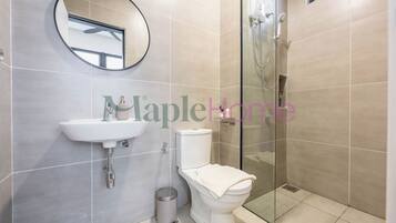 Ein modernes Badezimmer mit Toilette, Waschbecken und einer Duschkabine aus Glas.