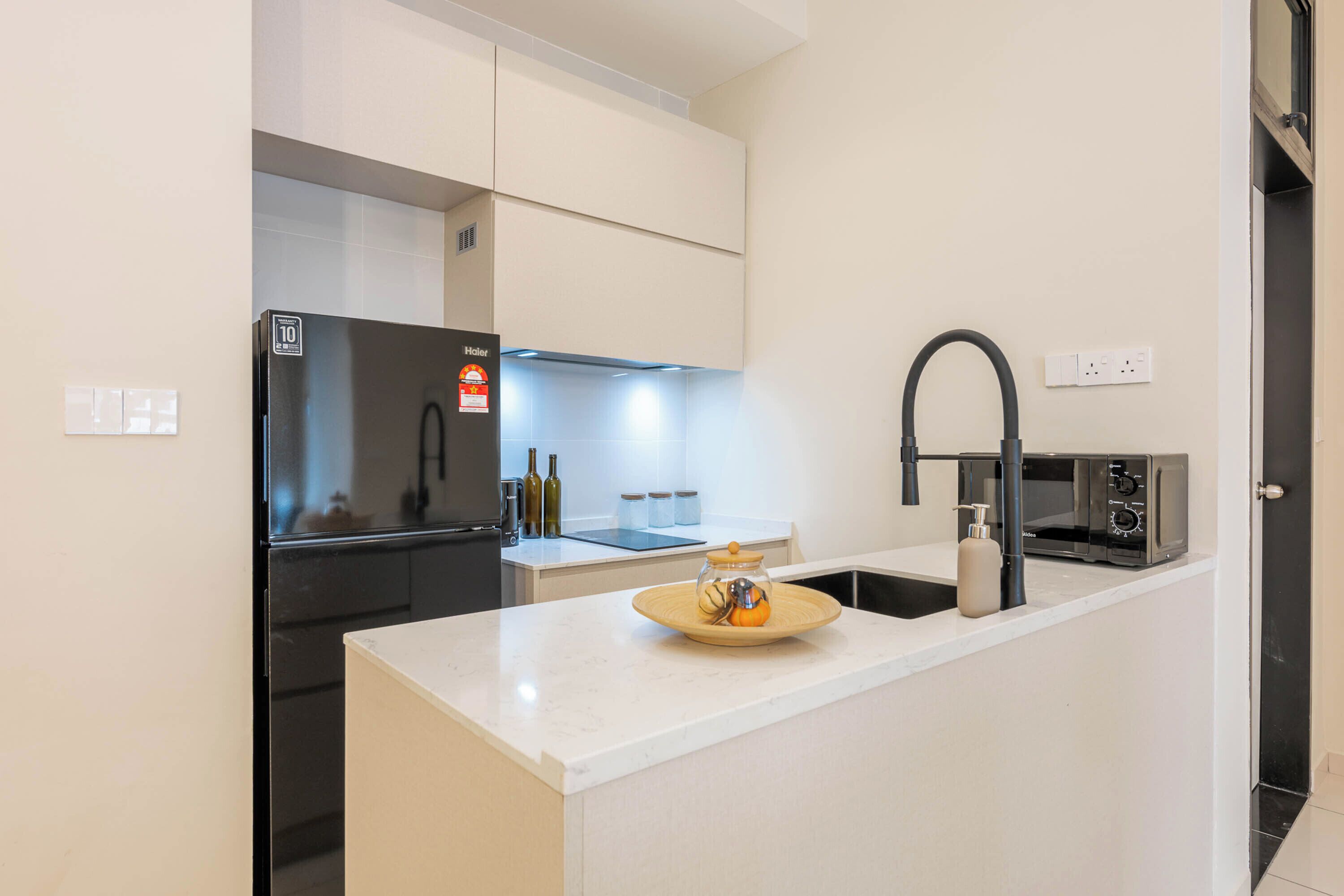 A modern kitchen with a built-in refrigerator, a microwave, and a sink with a black faucet.