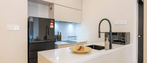 A modern kitchen with a built-in refrigerator, a microwave, and a sink with a black faucet.