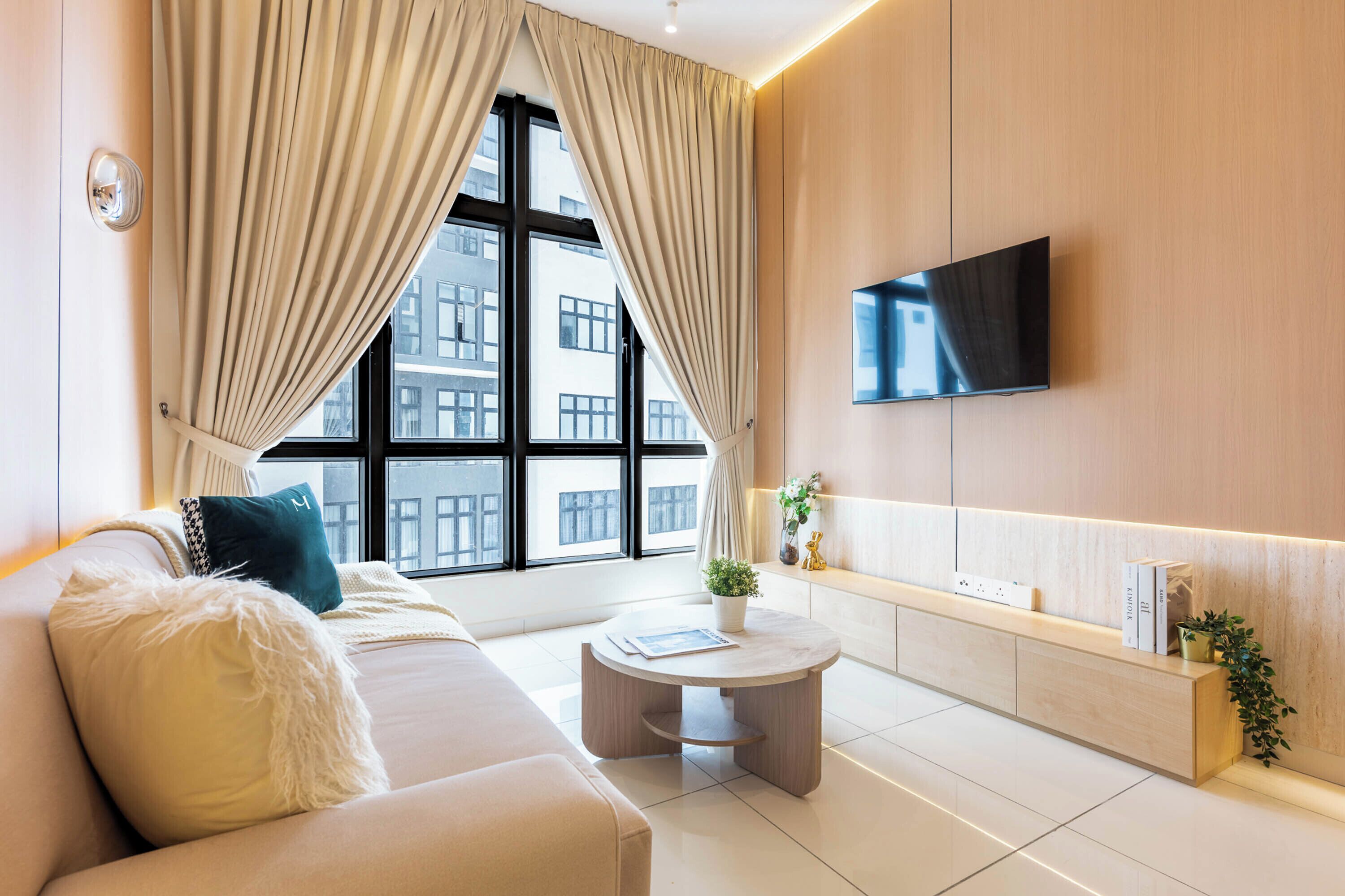 A modern living room with a sofa, coffee table, and a flat-screen TV mounted on the wall.