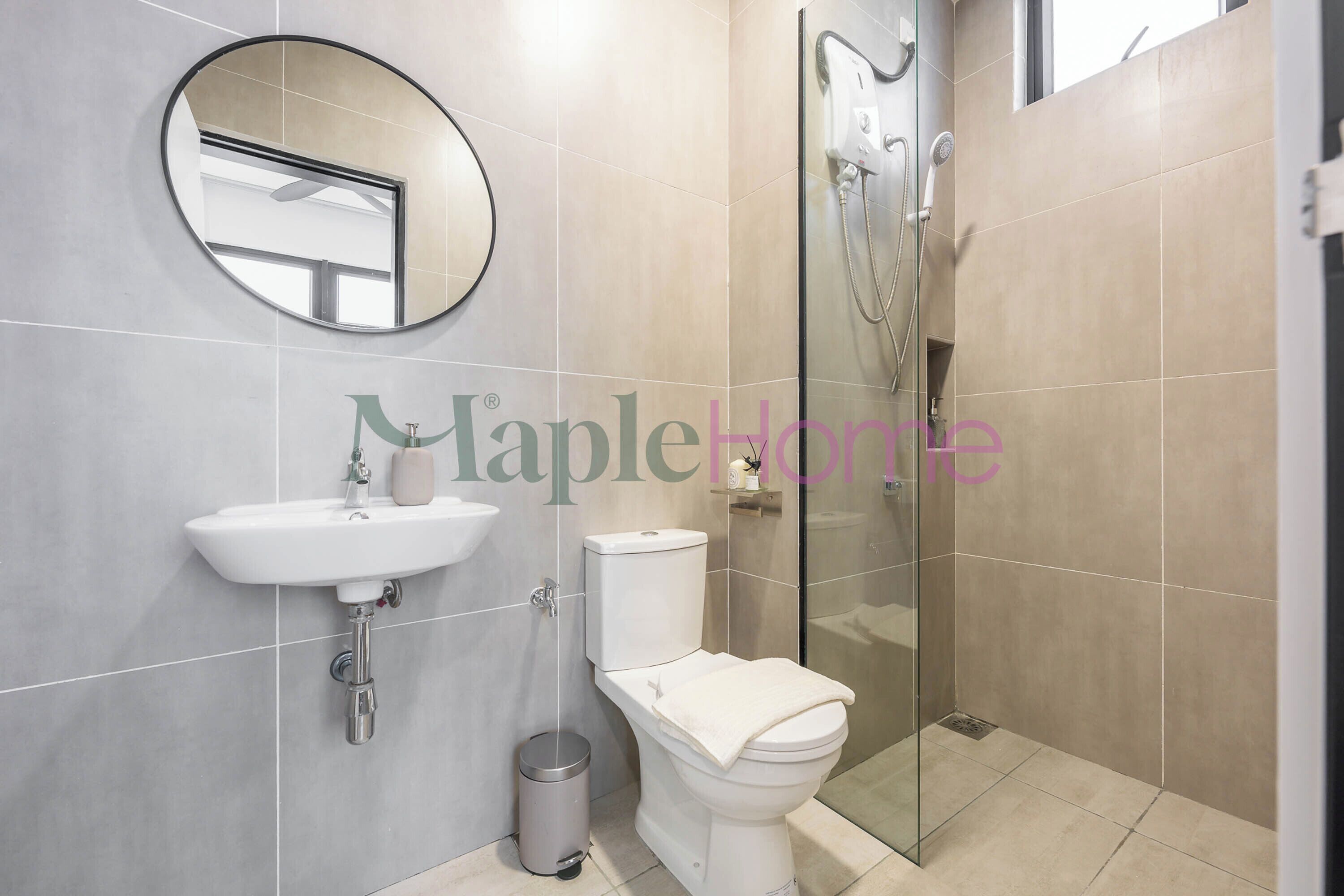 Un baño moderno con lavamanos, inodoro y ducha con mampara de vidrio.