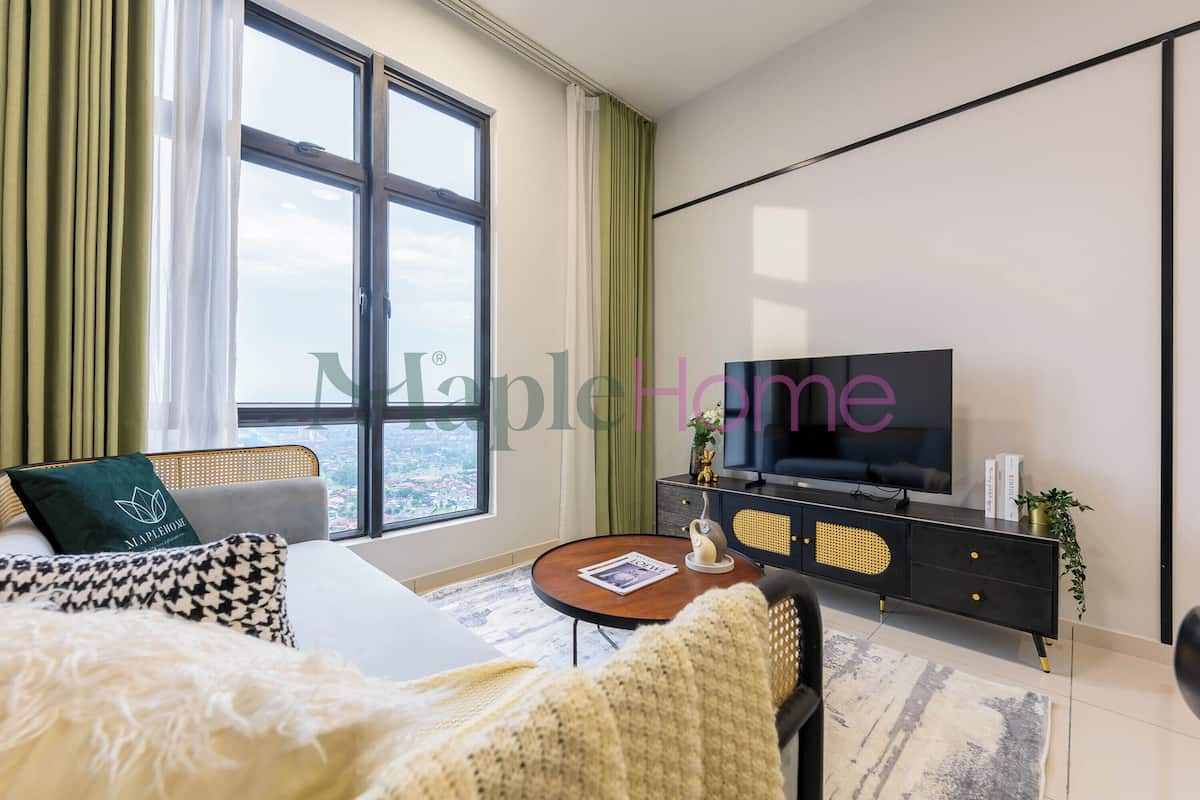 Een moderne hotelkamer met een groot raam, een flatscreen televisie, een bank, een klein rond tafeltje en een zwarte console met decoratieve objecten.