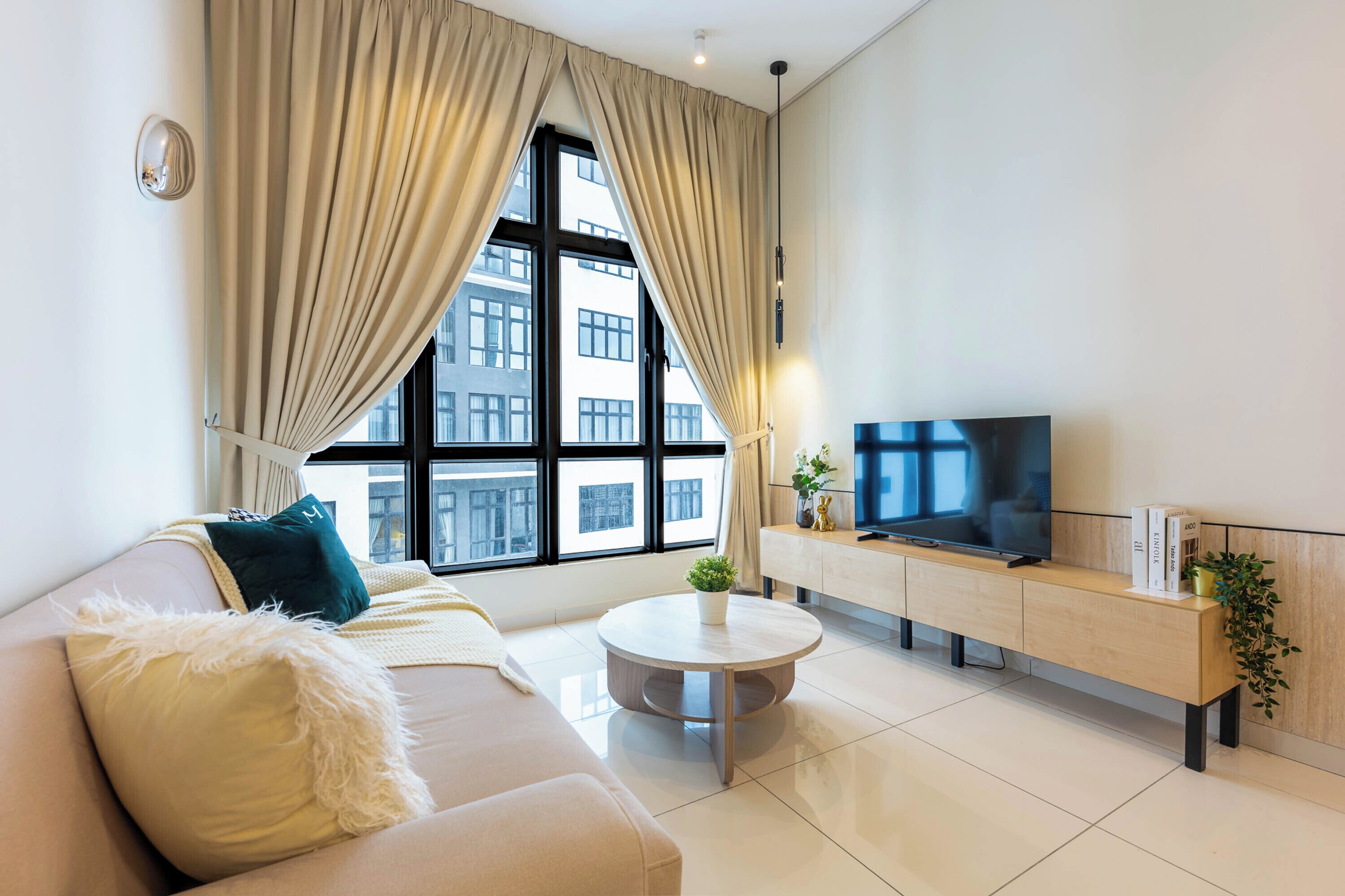 Una sala de estar moderna con un sofá, una mesa de centro, un televisor y una ventana con cortinas.
