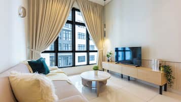 Una sala de estar moderna con un sofá, una mesa de centro, un televisor y una ventana con cortinas.