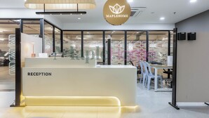 Un espace d’accueil au design moderne, comprenant un comptoir de réception portant l’inscription « RÉCEPTION » et un logo placé au-dessus.