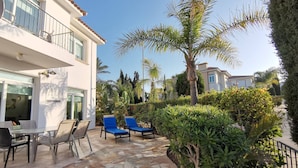A patio with stone flooring, outdoor seating, and a palm tree. - Artemis Villa in Protaras 100m From the Sea (Paralimni)