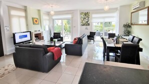 A spacious living area with a sofa, a dining table, and a TV. - Artemis Villa in Protaras 100m From the Sea (Paralimni)