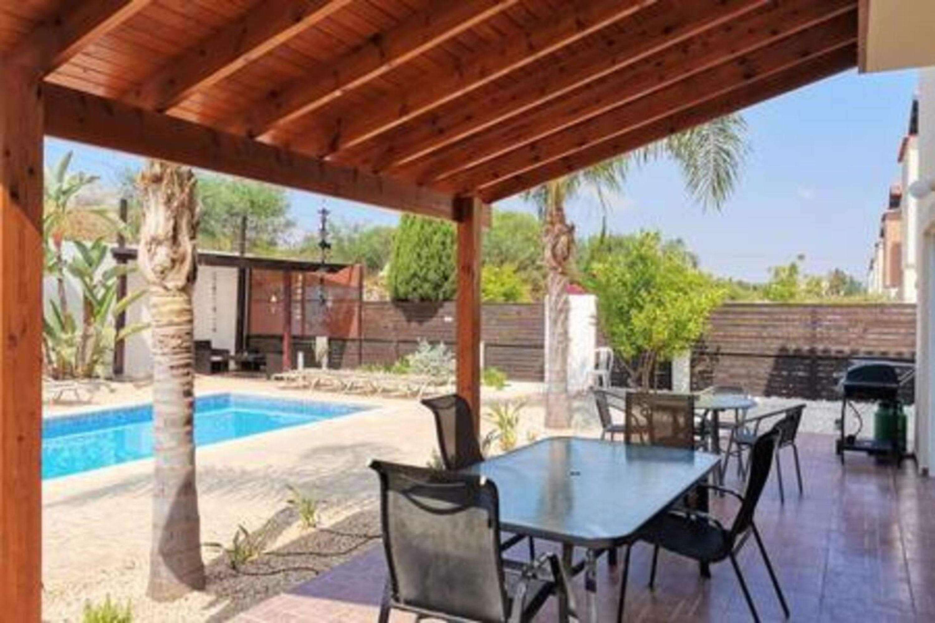A covered patio area with a pool, outdoor seating, and a view of the surrounding landscape.