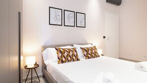 Une chambre d’hôtel avec un lit, des oreillers, une lampe de chevet et des œuvres d’art murales.