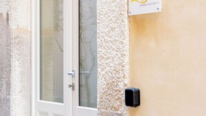 Une porte blanche avec un panneau de verre, une petite plaque portant le nom «Dimora Mattéotti», et un interphone noir fixé au mur.