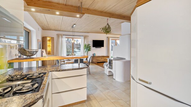 Una cocina moderna con techo de madera, estufa integrada y refrigerador blanco.